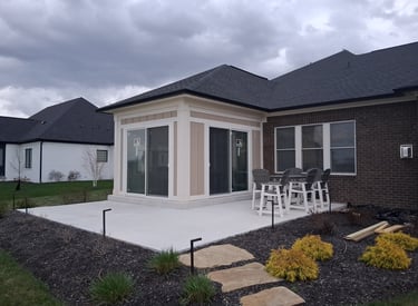 New patio enclosure finished with panel siding and white trim around two sliding glass doors.