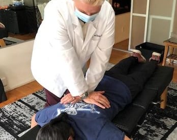 Dr. Lonna Denny performing a traditional spinal adjustment to a patient.