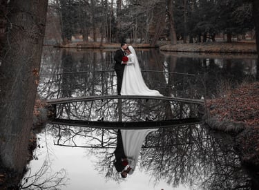 a bride and groom standing on a bridge over a pond