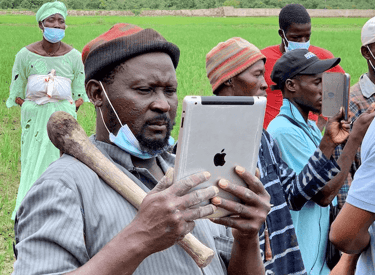 Homme avec chapeau utilisant une tablette pour agriculture durable en Afrique