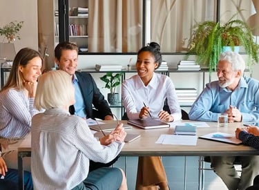 En grupp av chefer har en gruppcoaching runt ett bord.