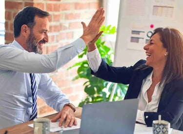 En mentor och en klient gör high five för ett framgångsrik mentorskap som skapat framgång för klienten..