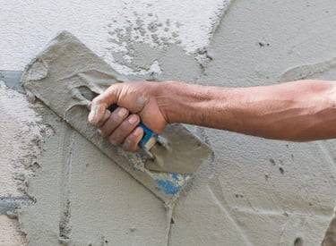 A person applying stucco to a wall.