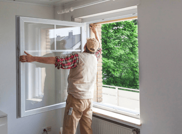 A window being installed into a wall by a person.