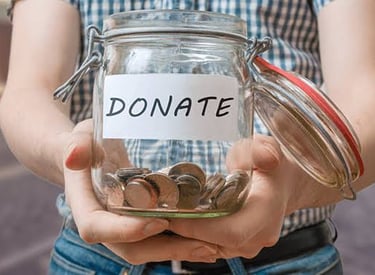 a person holding a jar with coins giving green Way Association