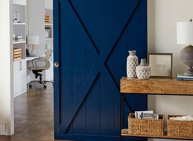 Large kitchen island with dark walnut wood countertop and white cabinetry on hardwood flooring.