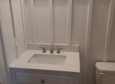 Modern white bathroom vanity with integrated sink and board and batten wall paneling.