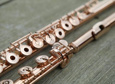 un flûte traversière en or rose posée sur une surface en bois