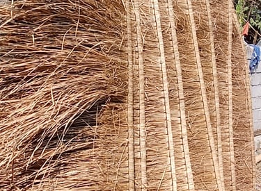 a man standing next to a pile of straw - wrapped straw - wrapped bale