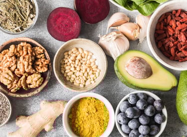 Flat lay of healthy superfoods including avocado, blueberries, walnuts, chia seeds, and turmeric powder.
