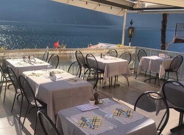 Terrazza di un ristorante con tavoli e sedie vista lago di Lugano