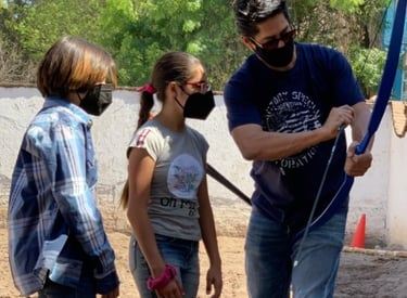 a man teaching arqueria ecuestre to two kids