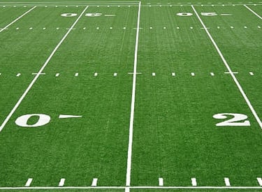 Striping a football field with a trueline grass and turf line marking paint striping machine.