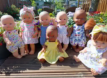 A group of Minikane dolls sitting on a wooden deck