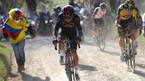a group of cyclists riding down a dirt road