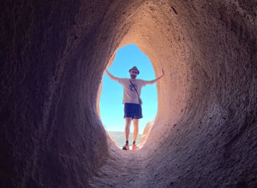 A man stands at the end of a tunnel leading to light