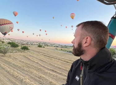 Man views the natural beauty of Cappadocia landscape from hot air balloon whilst watching sunrise