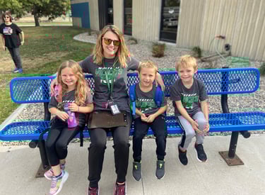 a woman sitting on a bench with three children