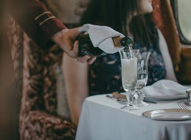 Champagne being poured onboard the Northern Belle luxury train dining experience.