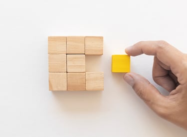 Hand pushes last piece of wood block to complete shape
