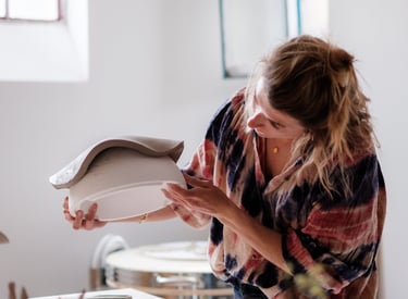 Une femme artisane qui regarde sa création en céramique dans son atelier