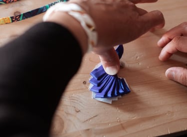 Une main d'artisane qui travaille sur un bijou en soie bleu