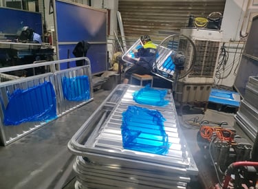 Professional welders fabricating aluminum frames in an industrial metal manufacturing workshop.