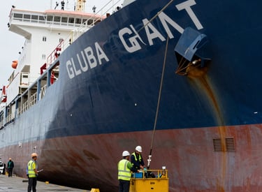 Marine engineer performing maintenance on a ship's engine at a dockside facility.