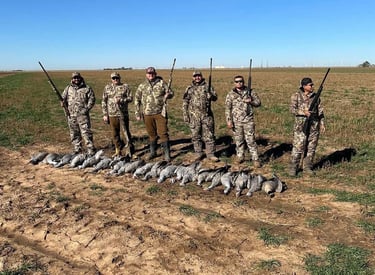 Group of hunters in camo standing in a field with harvested Sandhill Cranes during a guided hunt in the Texas Panhandle