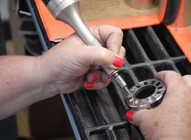 A technician performs precision metal deburring on a circular industrial component using a pneumatic handheld tool.