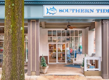Southern Tide storefront entrance with blue brand signage and outdoor seating area.