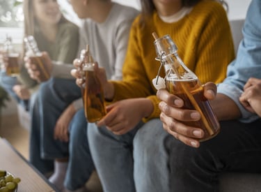 Un grupo de amigos sosteniendo botellas de vidrio con kombucha orgánica.