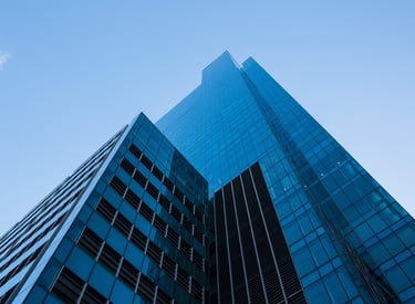 Low angle view of a modern blue glass skyscraper and office building against a clear sky.