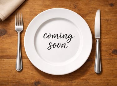 A white plate with “Coming Soon”, with a fork on the left and knife on the right.