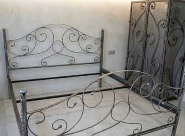 Ornate handcrafted wrought iron bed frame and matching metal armoire with scrollwork designs.
