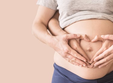 a pregnant woman holding her hands in the shape of a heart