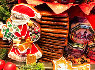 Hand-decorated gingerbread Santa and other spiced biscuits, with festive tins and pine cones, for a Christmas market display.