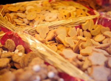 Assorted gourmet butter cookies and shortbread biscuits in rustic wicker baskets at a bakery market stall.