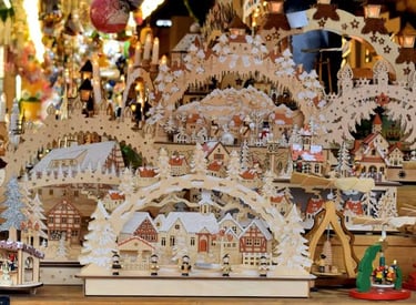 Handcrafted German wooden Christmas candle arches and village scenes at a festive holiday market.