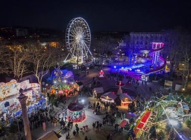 Aerial view of a festive Christmas market at night with a glowing Ferris wheel and carnival rides.