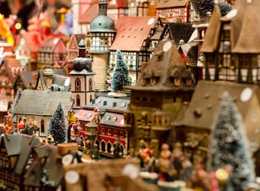 Handcrafted miniature German Christmas village with traditional timber-framed houses and snow-covered trees.
