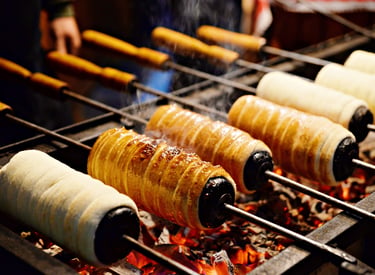 Traditional Hungarian chimney cakes roasting over hot coals at a European Christmas market.