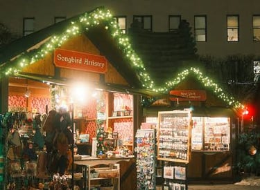 A festive outdoor Christmas market stall at night decorated with string lights and selling artisan gifts.