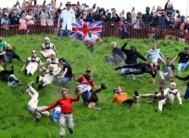 Competitors chase a wheel of cheese down a steep grassy hill during the Cooper's Hill Cheese-Rolling event.