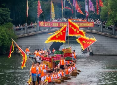 Traditional Chinese dragon boat race with participants rowing under a stone bridge decorated with red flags.