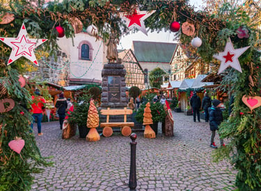 Traditional Christmas market in Eguisheim, France, featuring festive star decorations and wooden stalls.