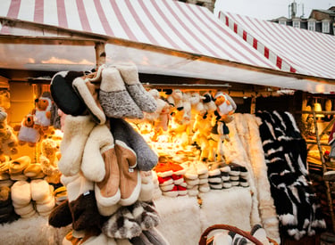 Handmade wool slippers and plush sheep toys displayed at a festive outdoor Christmas market stall.