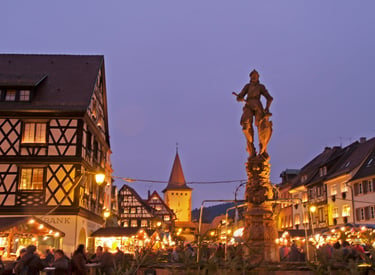 Gengenbach Christmas market at dusk featuring half-timbered houses and the knight statue fountain.