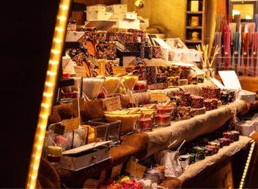 Handmade candles and aromatic incense displayed at a festive outdoor European Christmas market stall.
