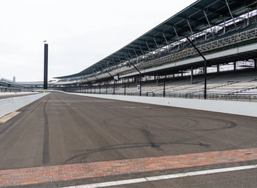 Indianapolis Motor Speedway finish line bricks and grandstands on a cloudy day.